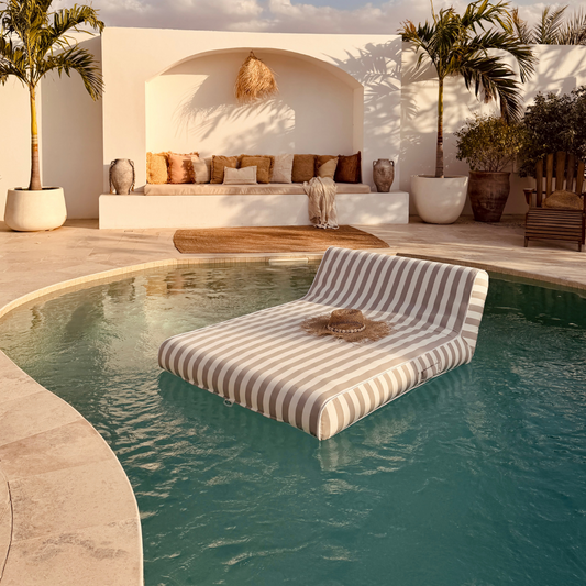 Striped lounge chair floating in a pool with a scenic background
