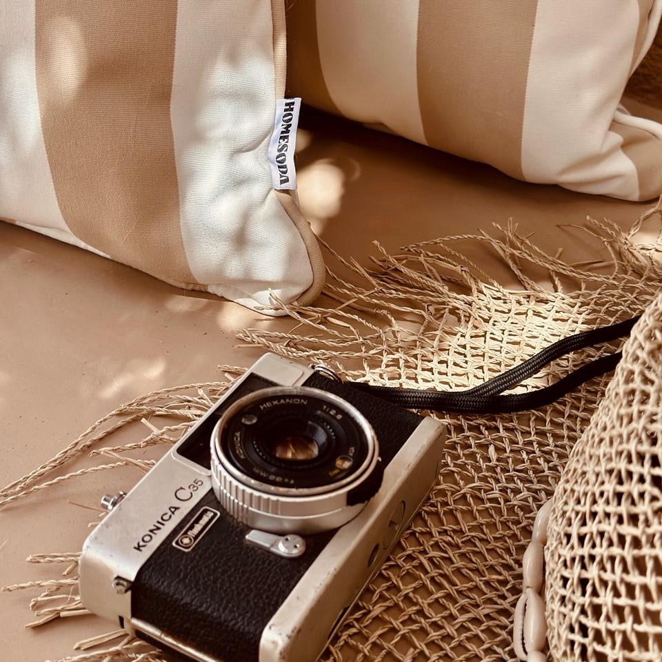 Vintage Konica camera on a textured surface with a beige pillow in the background