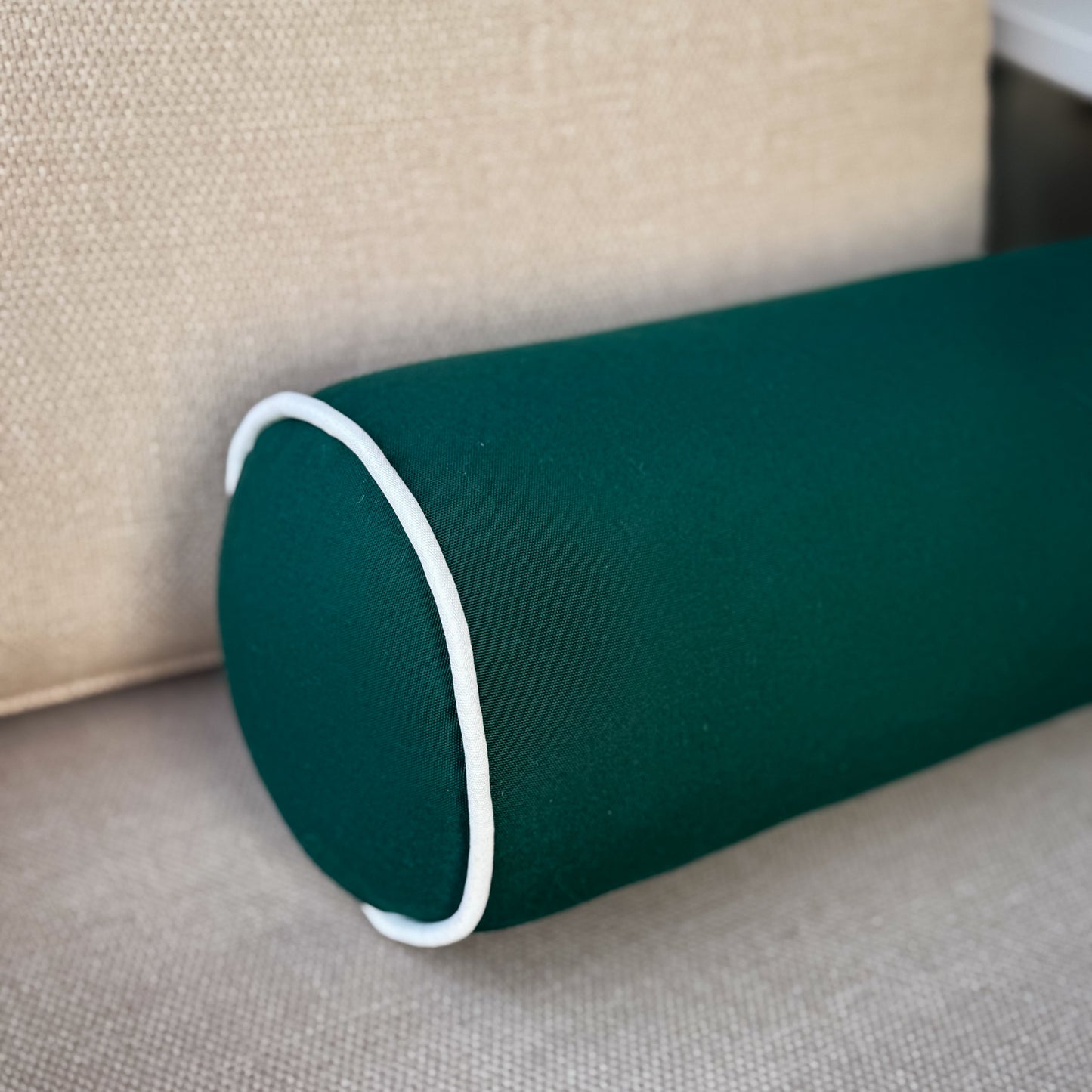 Green cylindrical pillow on a beige couch