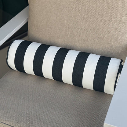 Chair with beige cushion and black and white striped bolster pillow on a neutral background