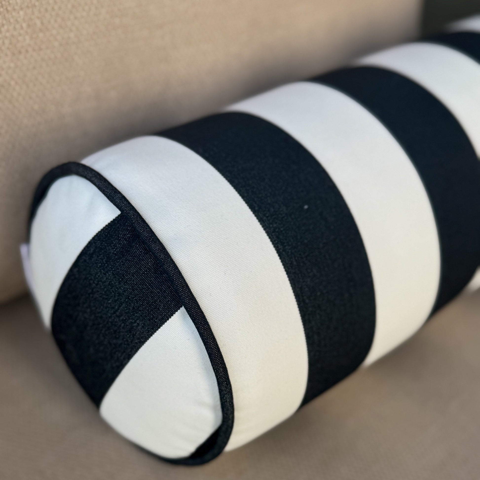 Black and white striped pillow on a beige surface