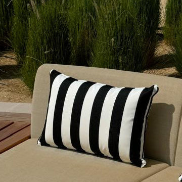 Beige outdoor sofa with black and white striped cushions against a natural background