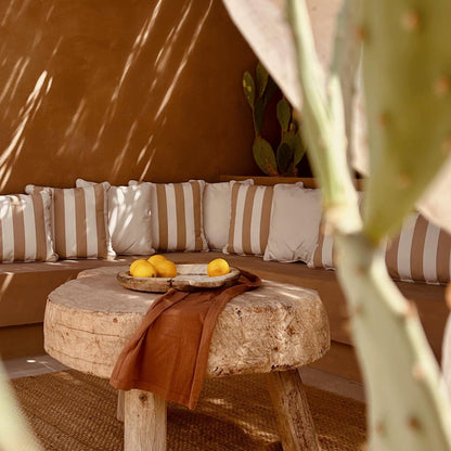 Cozy outdoor seating area with striped cushions, a small table, and cacti in the foreground.
