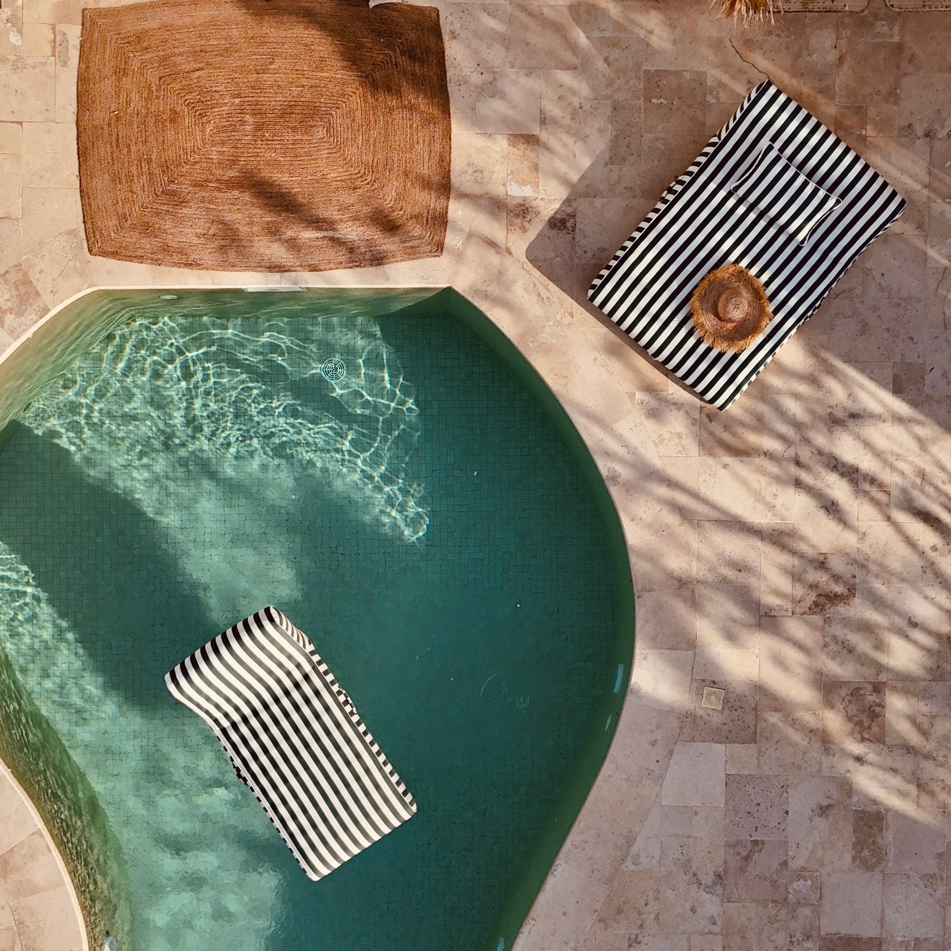 Outdoor setting with a pool, lounge chairs, and decorative elements.